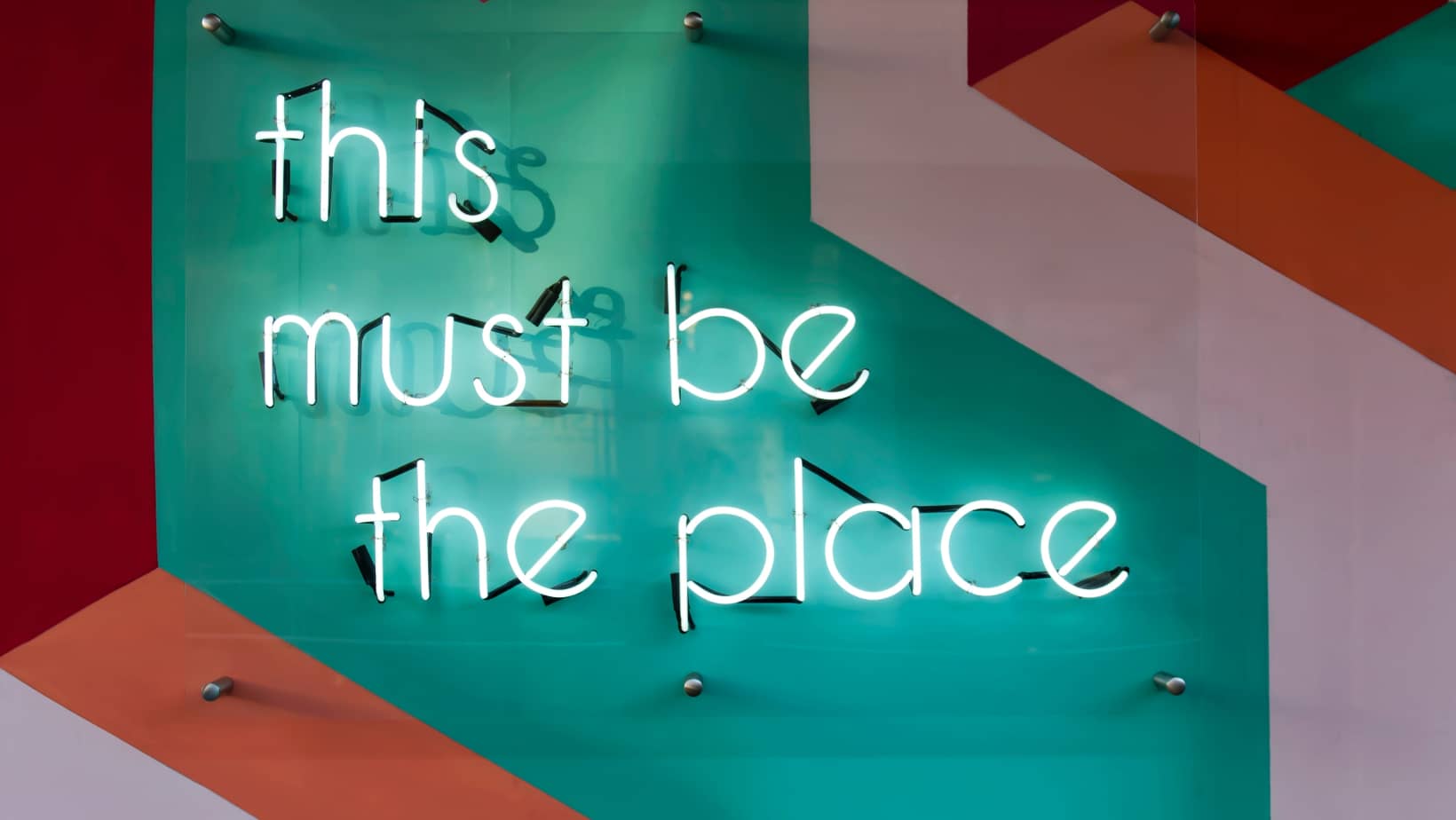 designer wall with neon sign "this must be the place"